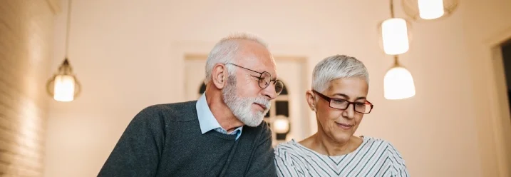 Ein älteres Paar macht seine Buchhaltung mit Taschenrechner und Stift.